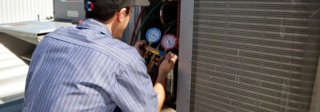 HVAC technician servicing a condenser unit in New Hyde Park
